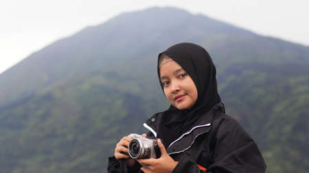 The woman wearing the hijab vacation at Spot New Selo with the background of Mount Merbabuの写真素材