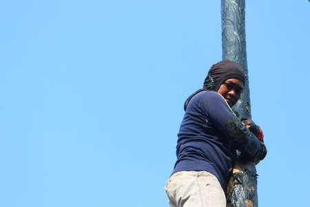 Traditional game from Indonesia named Panjat Pinang. This game won prizes that were mounted on top of the areca tree by climbing.のeditorial素材
