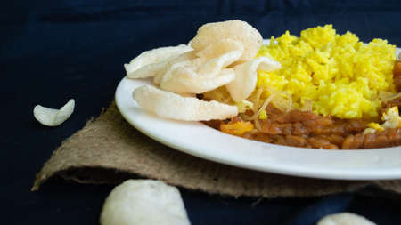 Nasi kuning or yellow rice, traditional food from Indonesia, for breakfast, combine wiith egg, tempeh, and crackers or kerupukの写真素材