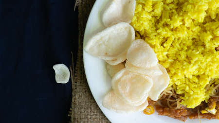 Nasi kuning or yellow rice, traditional food from Indonesia, for breakfast, combine wiith egg, tempeh, and crackers or kerupukの写真素材