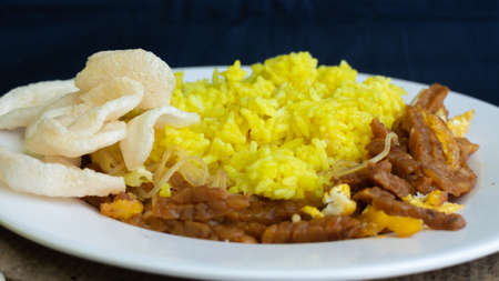 Nasi kuning or yellow rice, traditional food from Indonesia, for breakfast, combine wiith egg, tempeh, and crackers or kerupukの写真素材
