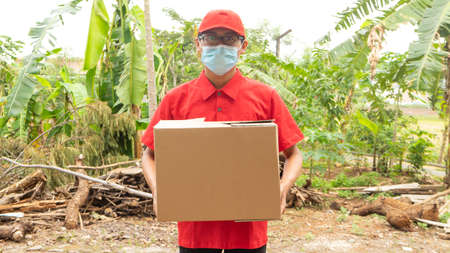 Asian young man delivery in red uniform with packagesの写真素材