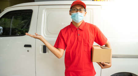 Asian young man delivery in red uniform with packages and hands look upの写真素材