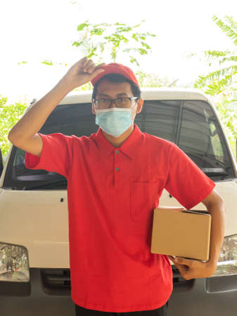 Asian young man delivery in red uniform with packagesの写真素材