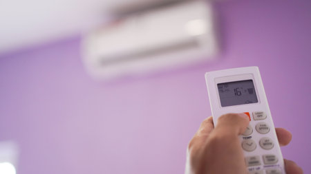 Close up of hand turn on air conditioner with remote controlの写真素材