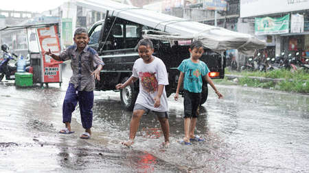 10 January 2020, Cirebon, Indonesia: child playing rain on roadのeditorial素材