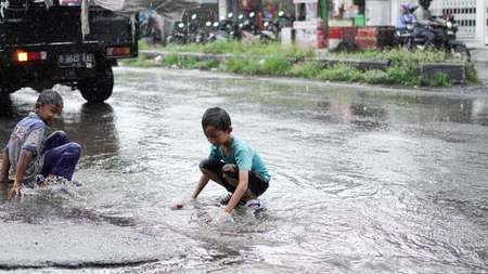 10 January 2020, Cirebon, Indonesia: child playing rain on roadのeditorial素材