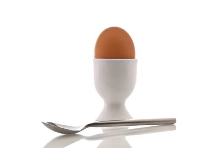 Egg in white cup with a spoon over white background 
の写真素材