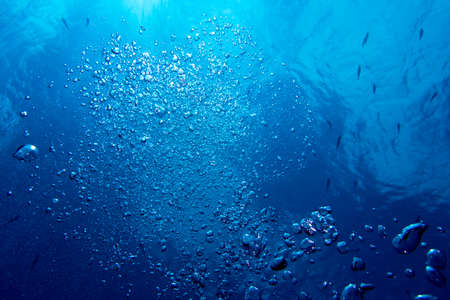 Bubbles from a diver rising to the surface in blue waterの写真素材