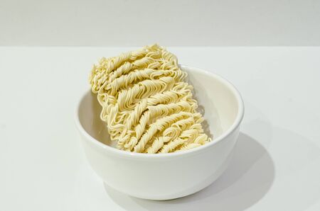 A raw instant noodle in a white bowlの写真素材