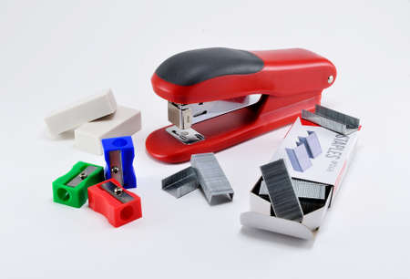 Office stapler and stapler staples, erasers and sharpeners on white background.