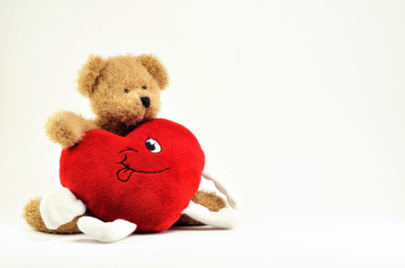 Brown Teddy bear toy and plush heart with handles, on white background.の写真素材
