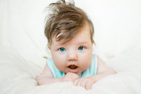 Blue-eyed baby lies on a soft blanket and looking forward.の写真素材