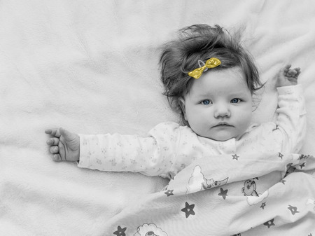 A small child with a yellow bow, black-and-white photograph.の写真素材