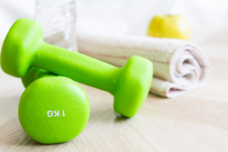 Green dumbbells, water bottle, apple and a towel. Set for sports. The concept of sport, a healthy lifestyle.の写真素材