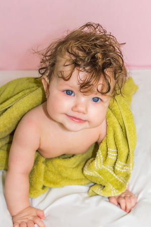 Little baby in a green towel after bathing, changing of diaper.の写真素材
