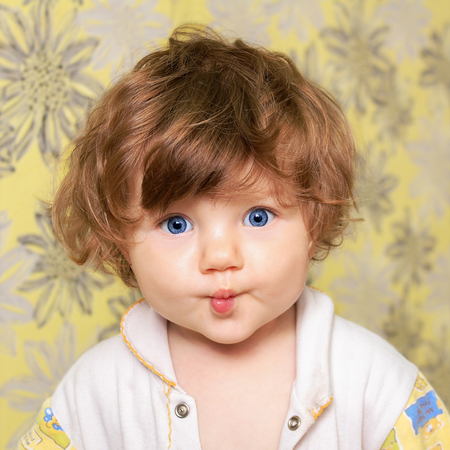 Funny little child folded bow lips, looking at the camera.の写真素材