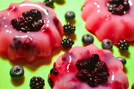 Pink puddings with fruits are on green background.の写真素材