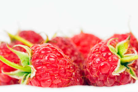 Macro photo about red ripe raspberries on white background.