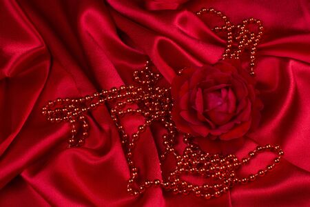 Red rose with red pearls are on red wricked satin.の写真素材