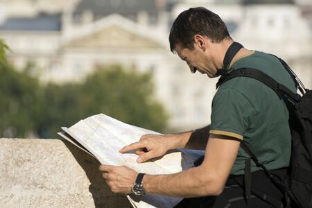 The tourist is looking at the map in the city.