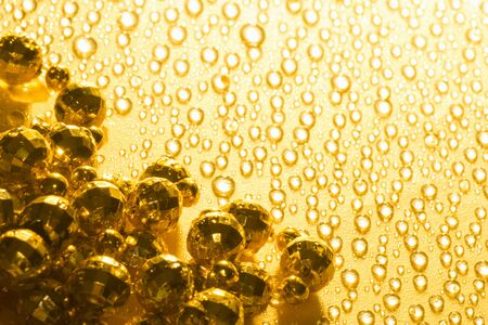 Shiny golden pearls are on golden background with water drops.の写真素材