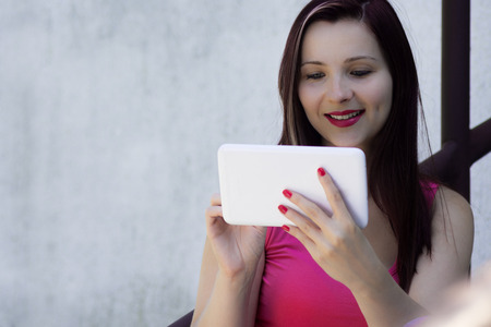 Smiling young woman is holding white tablet.の写真素材