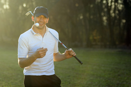 Portrait of cheerful golf player with putter and ball.の写真素材