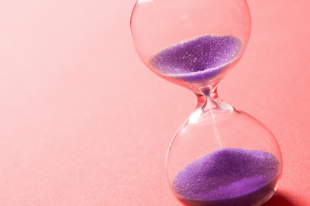 Purple sand clock is on bright red background.