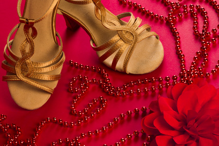 Latin dance shoes with red pearls and rose on red background.の写真素材