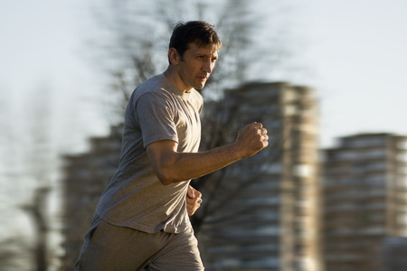 The man is running as recreation outdoors at the city.
