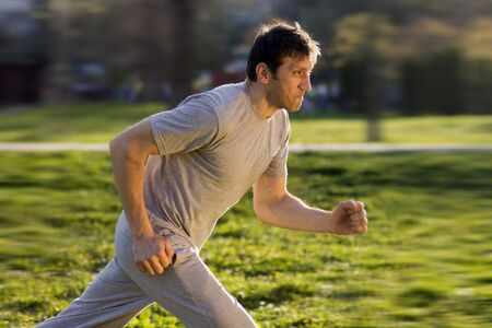 The man is running outdoors at the park.