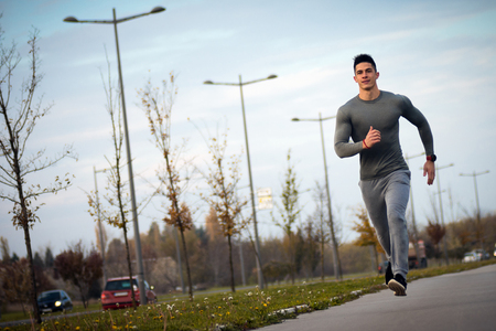 The sporty young man is jogging on the street.の写真素材