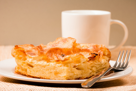 Close-up photo of pie for breakfast with fork and white mug of milk or yogurt on gray background.の写真素材