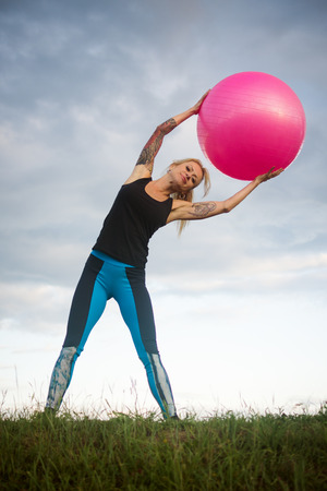 The attractive middle aged woman is exercising with Fitness ball outdoors.の写真素材