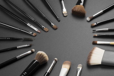 Different make-up brushes are in heart shape on gray background, loving make-up concept.の写真素材