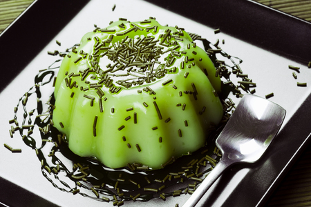 Green pudding sweet dessert from kiwi is served on black plate.の写真素材