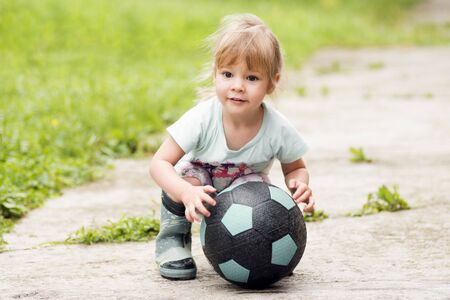 The cute little girl is playing with soccer ball on the street.の写真素材