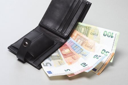 Paper currency euro banknotes are in black purse on gray background.