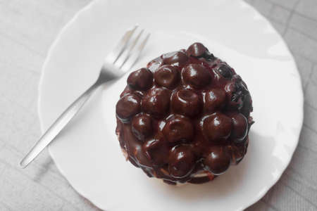 Delicious fruity chocolate cake with sour cherry on white plate with fork.
