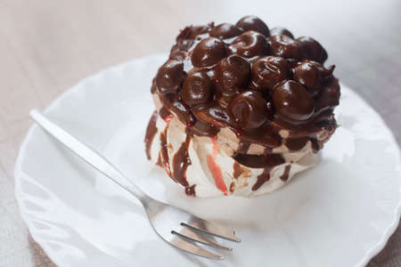 Delicious sweet dessert chocolate cake with cherry on white plate with fork.の写真素材