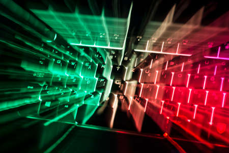 Illuminated green and red magical computer keyboard on black background.