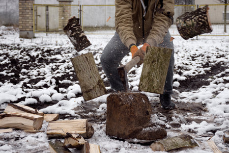 The lumberjack or woodcutter is cutting the firewood on snow at winter.