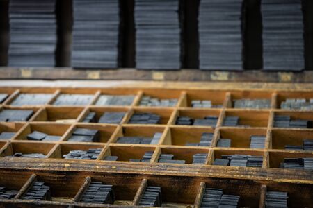 Printing press letter blocks in a wooden shelf.