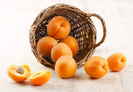 Fresh apricots in the basket on a wooden tableの写真素材