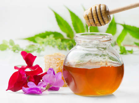 Honey with wood stick and flowersの写真素材