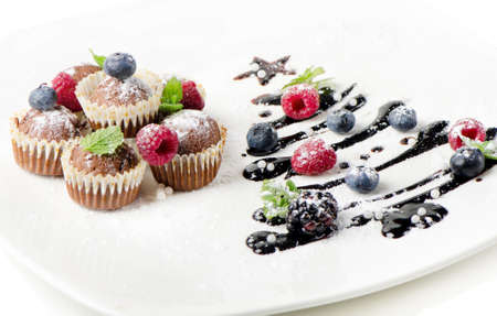 Cupcakes  and sweet  christmas tree with berries  isolated on whiteの写真素材