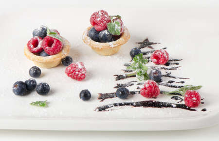 sweet christmas tree with berries on a white plateの写真素材