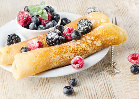Crepes with berries on a wooden tableの写真素材