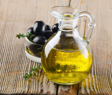 Olive oil and black olives on a wooden tableの写真素材